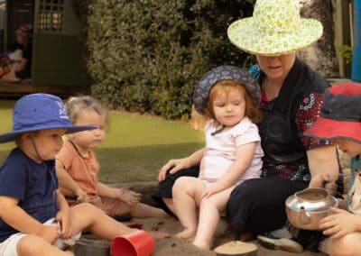 Early Childhood Educator - Female sitting outside with children to play together